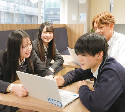 ソファ席でノートパソコンを囲んで話す生徒たち
